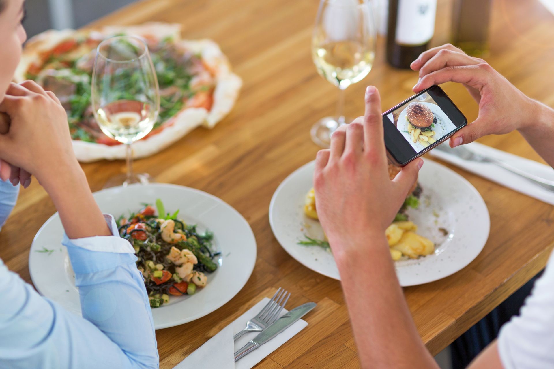 Friends with smartphone photographing food at cafe
